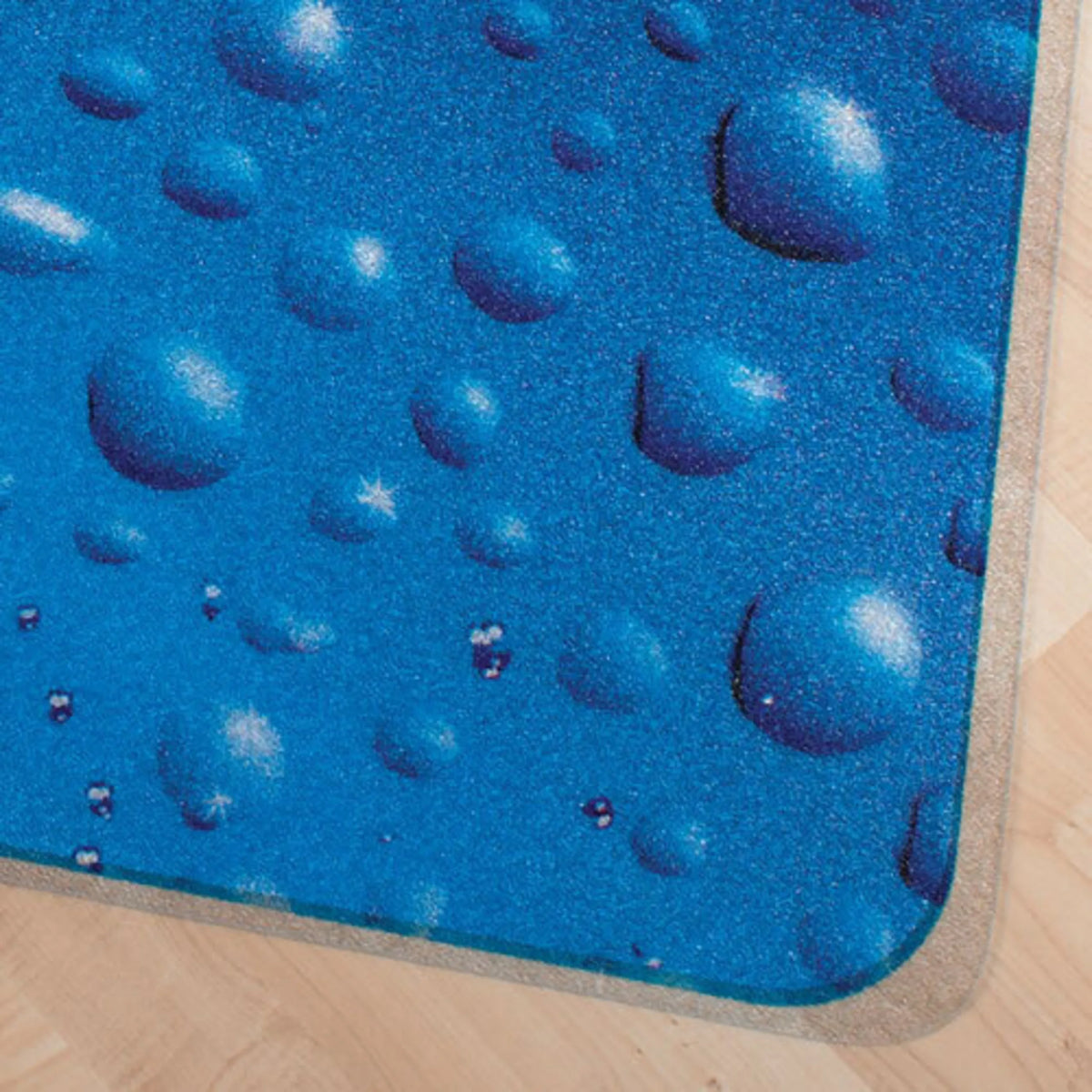 Wassertropfen-Motiv der Bodenschutzmatte ULTIMAT 90x120 in Blau auf hellem Holzboden von Floortex