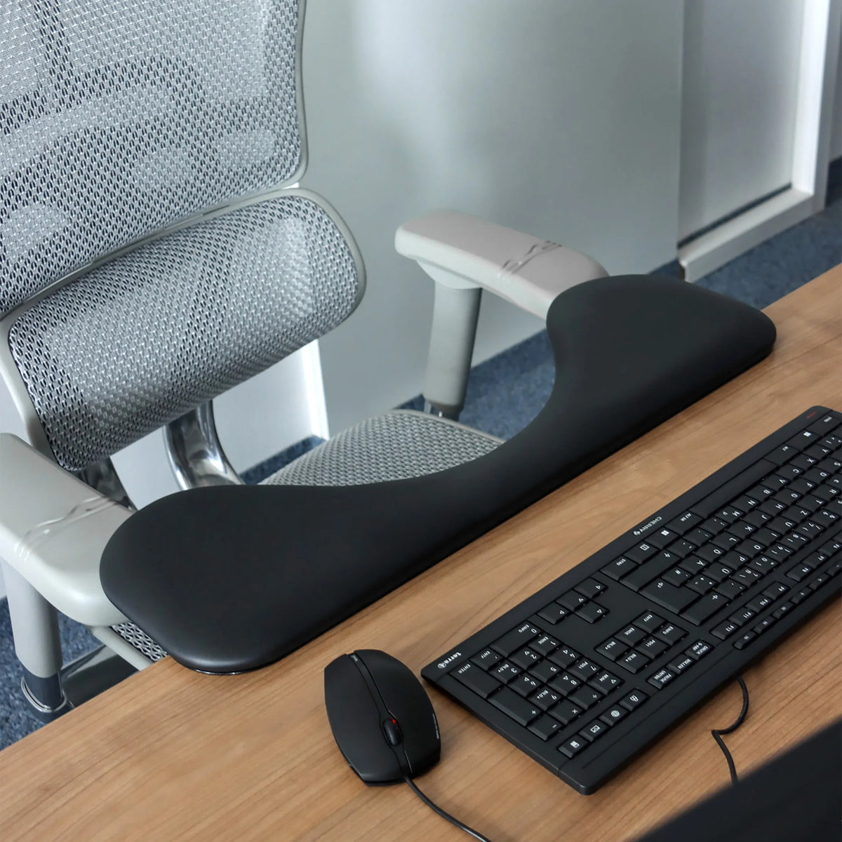 Schwarze Armstütze RELEX RT2 auf einem Schreibtisch neben einer Tastatur und einer Computermaus von hjh OFFICE